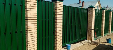 Забор из евроштакетника на желтых кирпичных столбах из декоративого кирпича фото